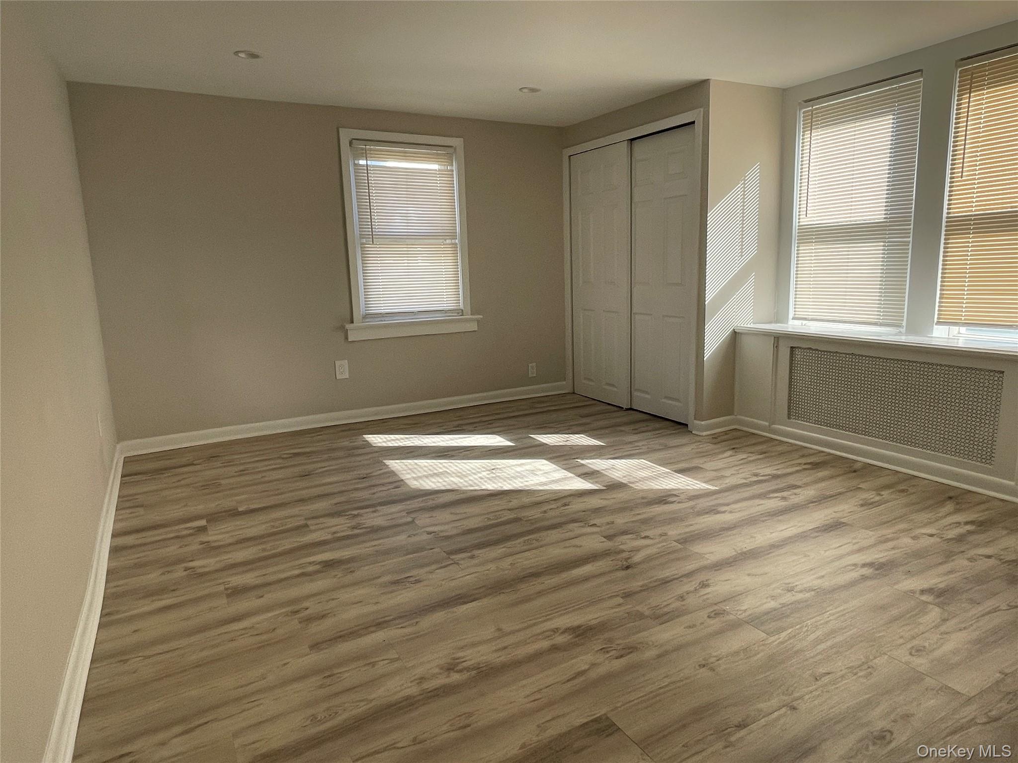 89 2nd Street, Unit 1 New Rochelle, NY 10801 - Photo 12 of 13 Unfurnished bedroom with light wood-style flooring, radiator heating unit, and a closet