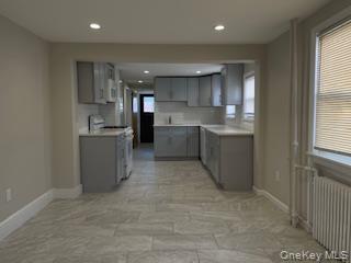 89 2nd Street, Unit 1 New Rochelle, NY 10801 - Photo 4 of 13 Kitchen featuring gray cabinets, radiator, tasteful backsplash, gas range gas stove, and light countertops
