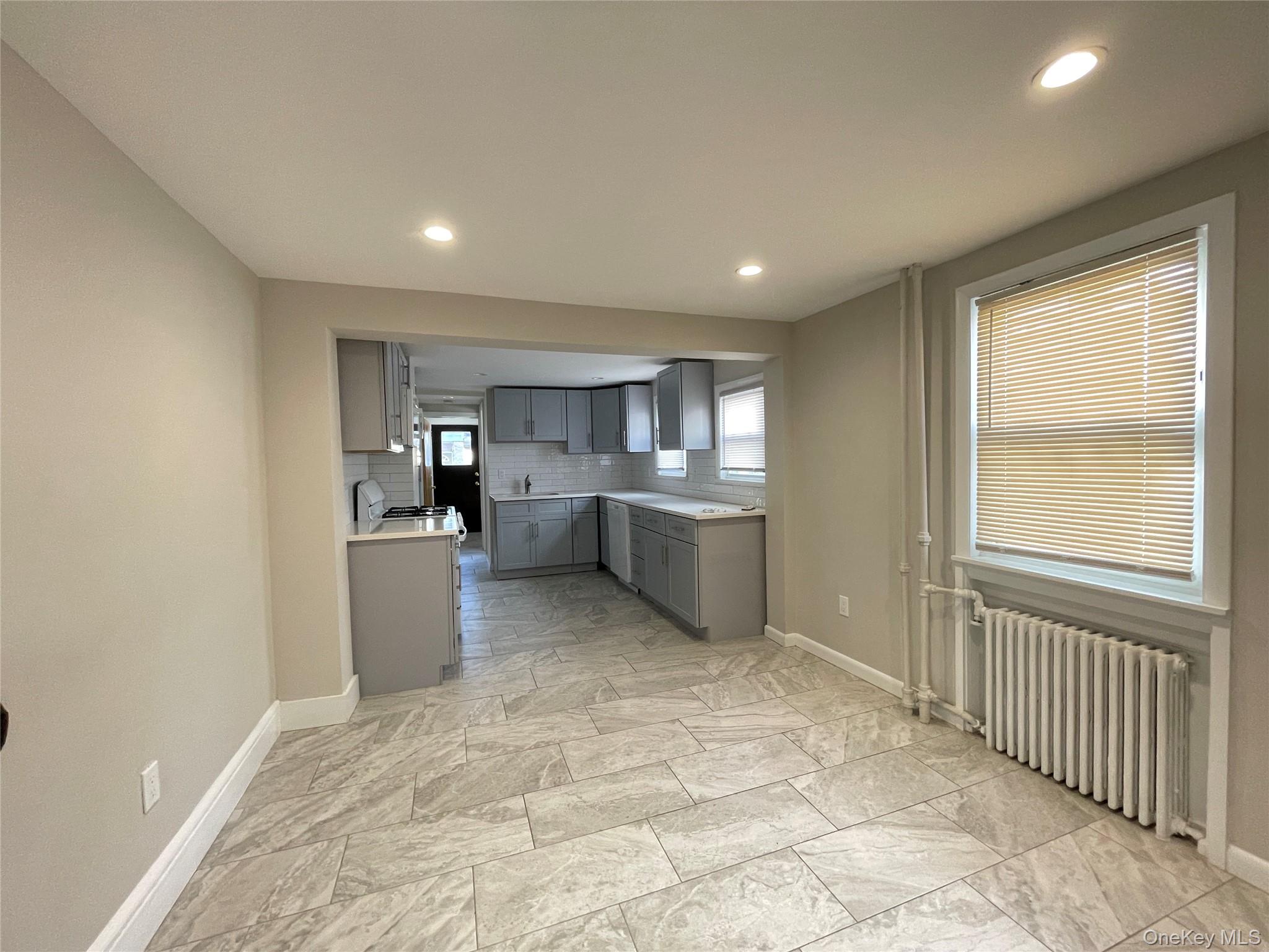 89 2nd Street, Unit 1 New Rochelle, NY 10801 - Photo 6 of 13 Kitchen with gray cabinets, radiator, decorative backsplash, and recessed lighting
