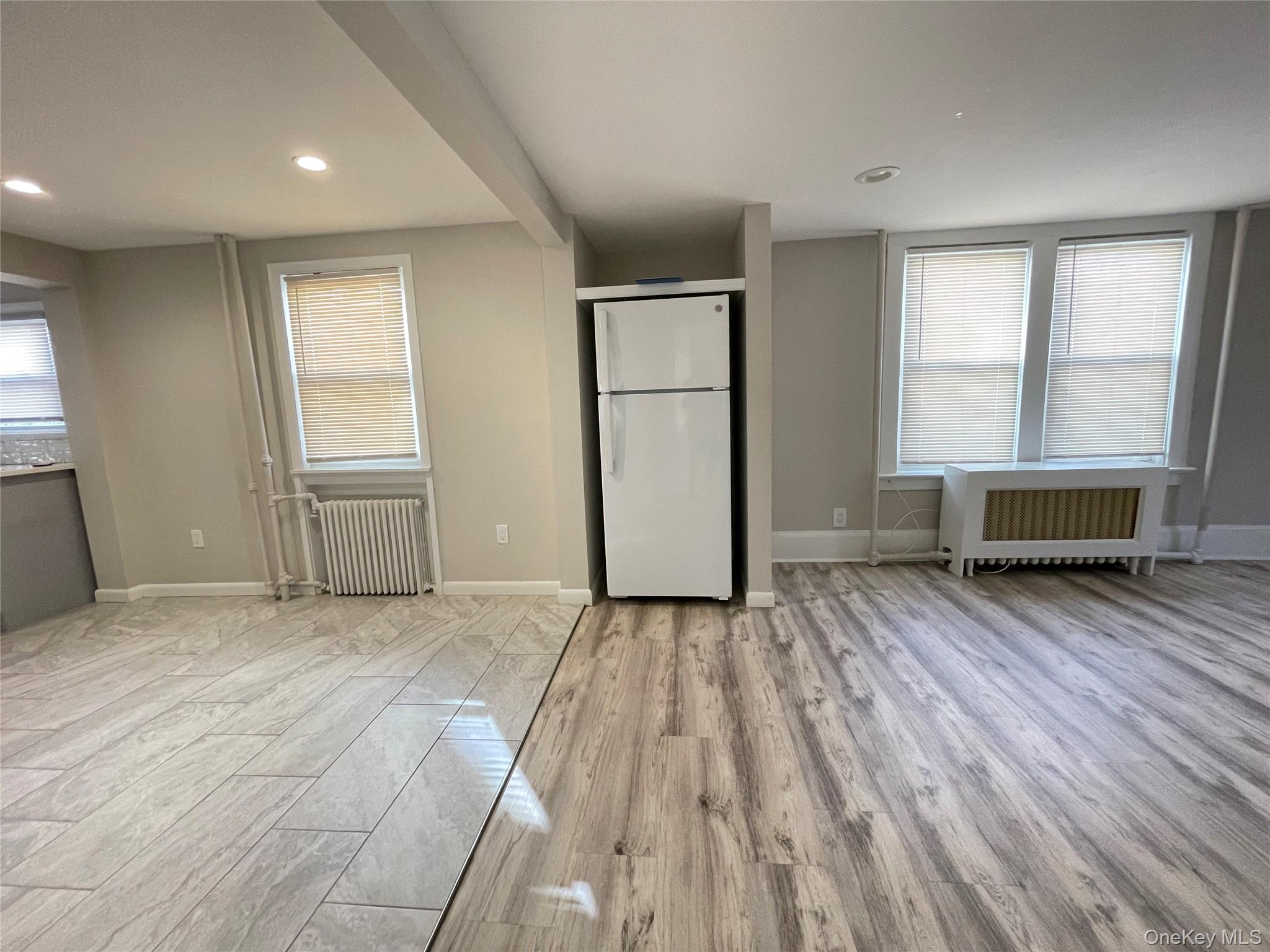 89 2nd Street, Unit 1 New Rochelle, NY 10801 - Photo 7 of 13 Unfurnished bedroom featuring freestanding refrigerator, light wood finished floors, radiator heating unit, and recessed lighting