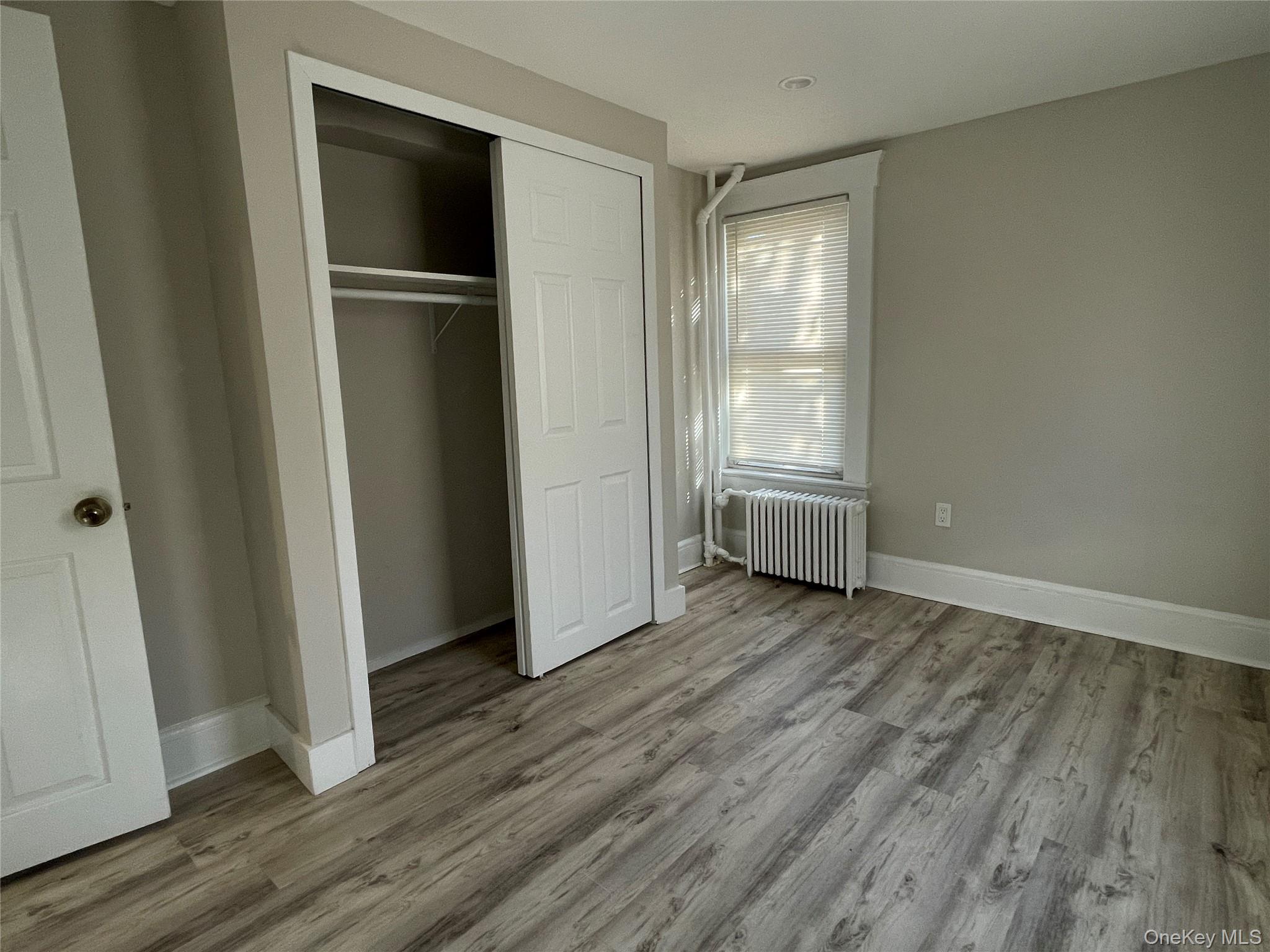 89 2nd Street, Unit 1 New Rochelle, NY 10801 - Photo 10 of 13 Unfurnished bedroom with radiator heating unit, light wood-type flooring, and a closet