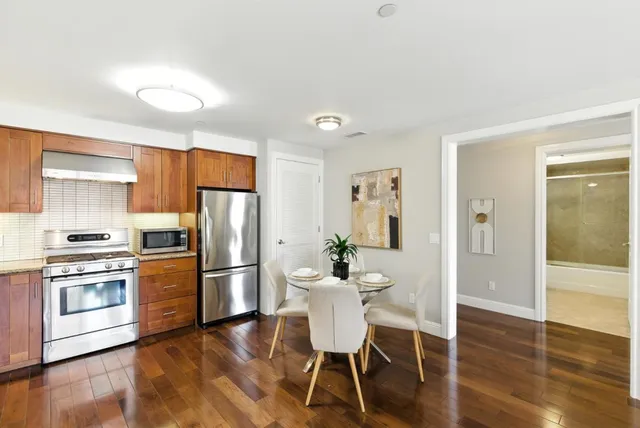 a kitchen with stainless steel appliances wooden floor and a refrigerator