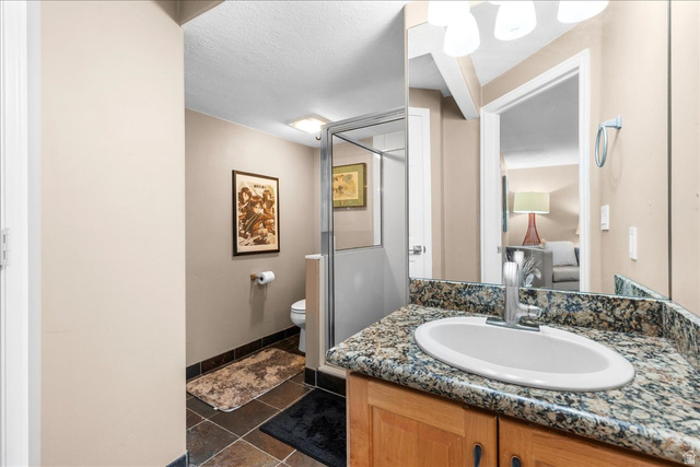 7824 South Sequoia Tree Lane Sandy, UT 84094 - Photo 32 of 43 Ensuite bathroom with a shower stall, vanity, and dark tile patterned floors