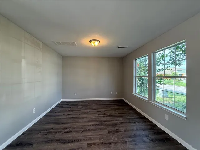 a view of an empty room with wooden floor and a window