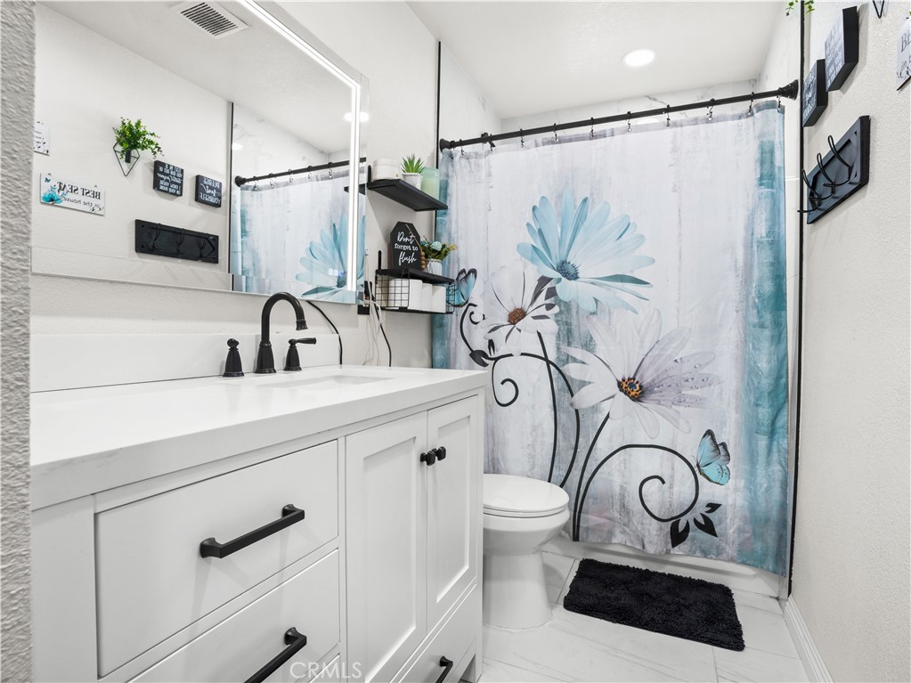 1455 North Alice Avenue Rialto, CA 92376 - Photo 16 of 23 a bathroom with a sink a mirror and a shower curtain