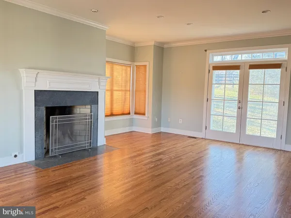 an empty room with wooden floor fireplace and windows