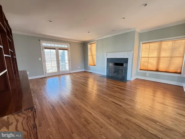 an empty room with wooden floor fireplace and windows