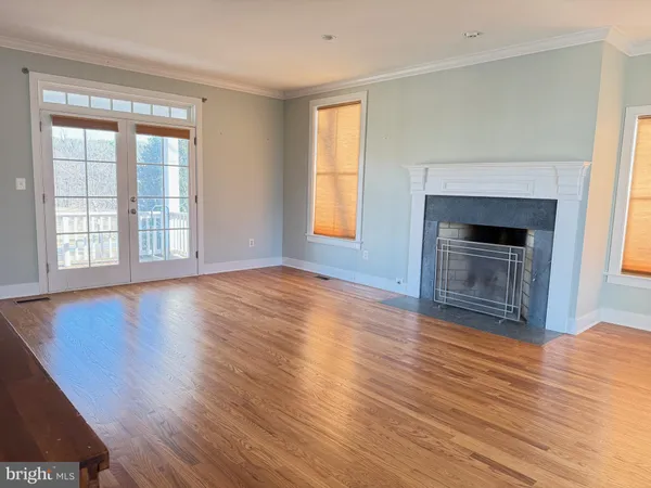 an empty room with wooden floor fireplace and windows