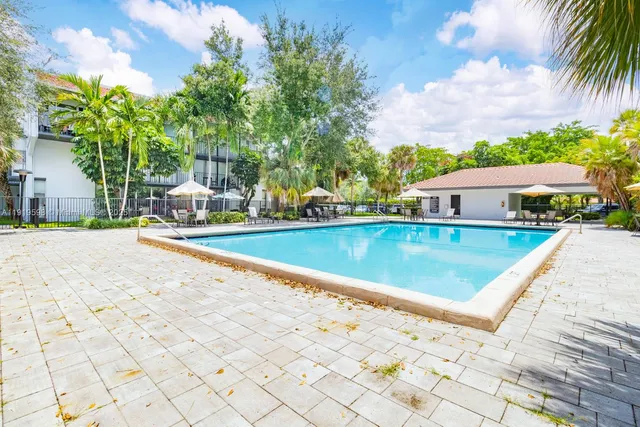 a view of swimming pool with lounge chair and palm trees