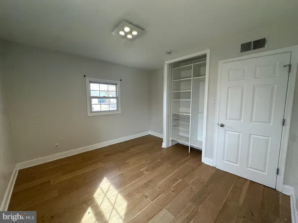 a view of empty room with wooden floor and window