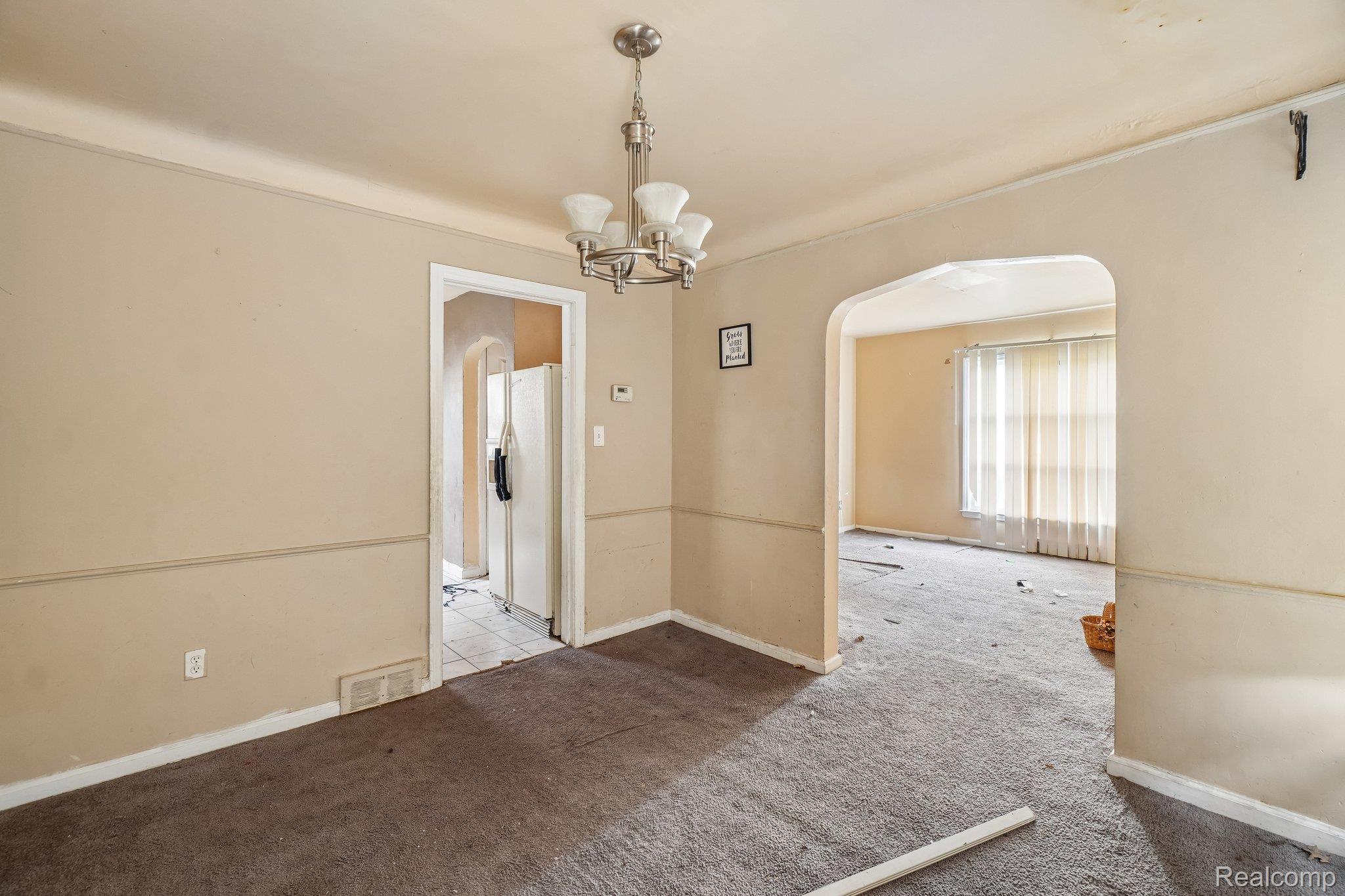5969 Cadieux Road Detroit, MI 48224 - Photo 11 of 24 Carpeted empty room with arched walkways and a chandelier