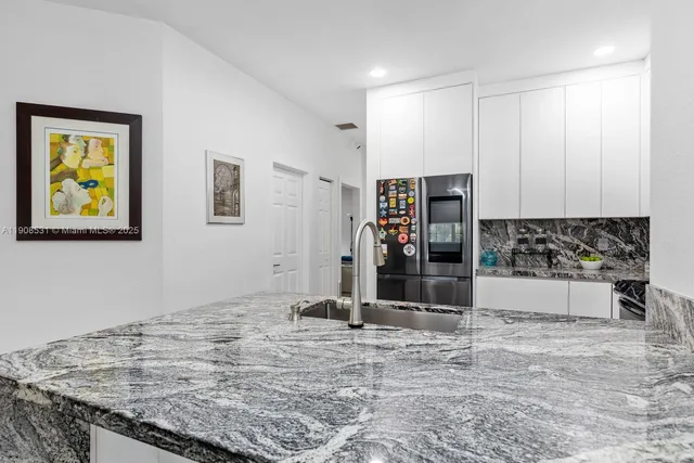 a view of kitchen with granite countertop sink and cabinets