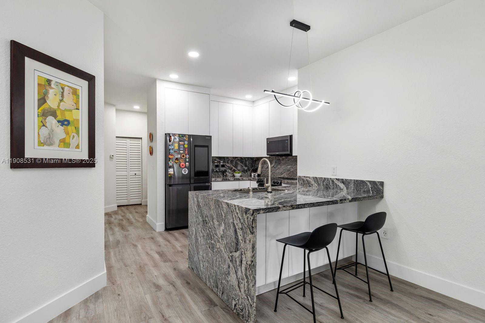 13216 Southwest 44th Street, Unit 11204 Miramar, FL 33027 - Photo 23 of 48 a view of a kitchen with kitchen island a dining table chairs stainless steel appliances and cabinets