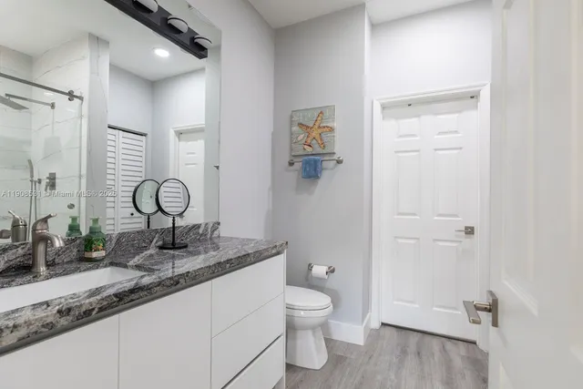 a bathroom with a granite countertop sink toilet and shower