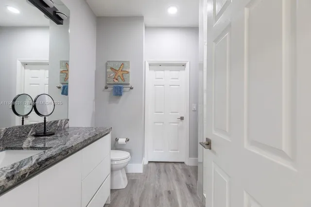 a bathroom with a granite countertop sink mirror vanity and toilet
