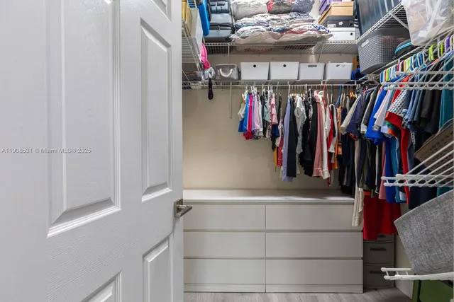 a view of walk in closet with clothes and shoes