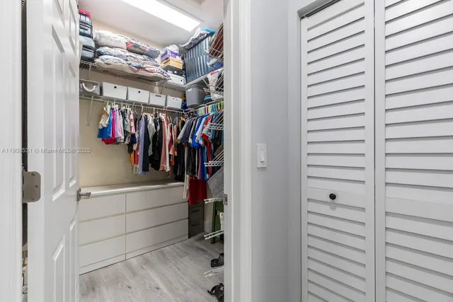 a view of walk in closet with clothes and shoes