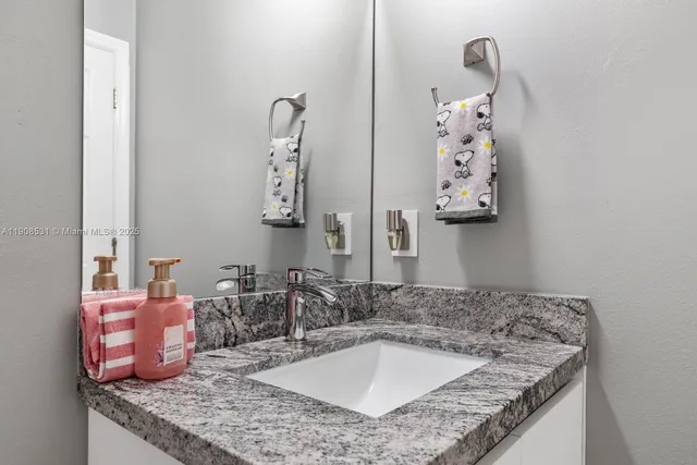 a bathroom with a granite countertop sink and a mirror