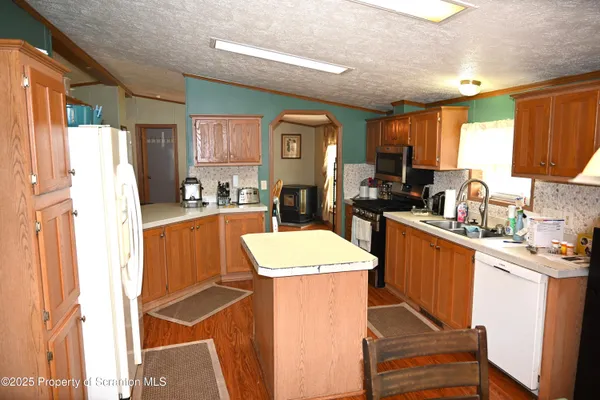 a kitchen with a refrigerator a stove a sink dishwasher and cabinets with wooden floor