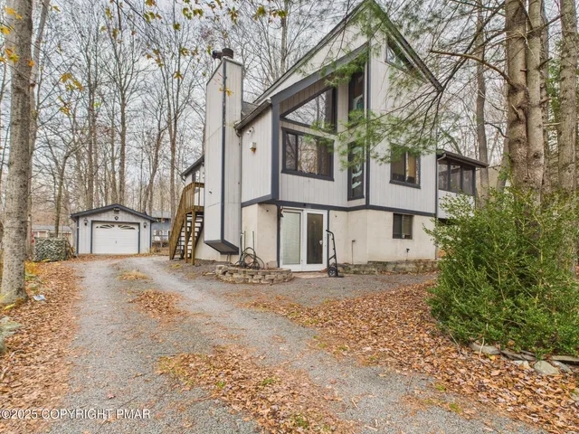 a view of large house with a large tree and wooden fence