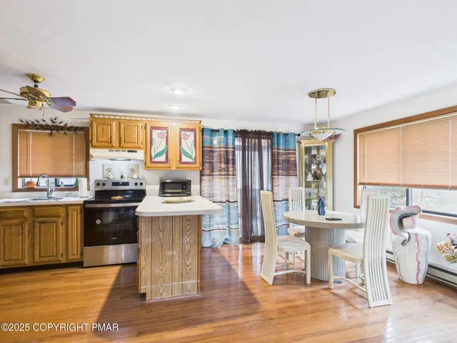 a open kitchen with granite countertop a stove top oven a sink and dishwasher wooden floor