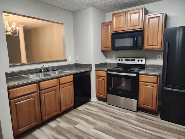 a kitchen with granite countertop wooden cabinets stainless steel appliances and a window