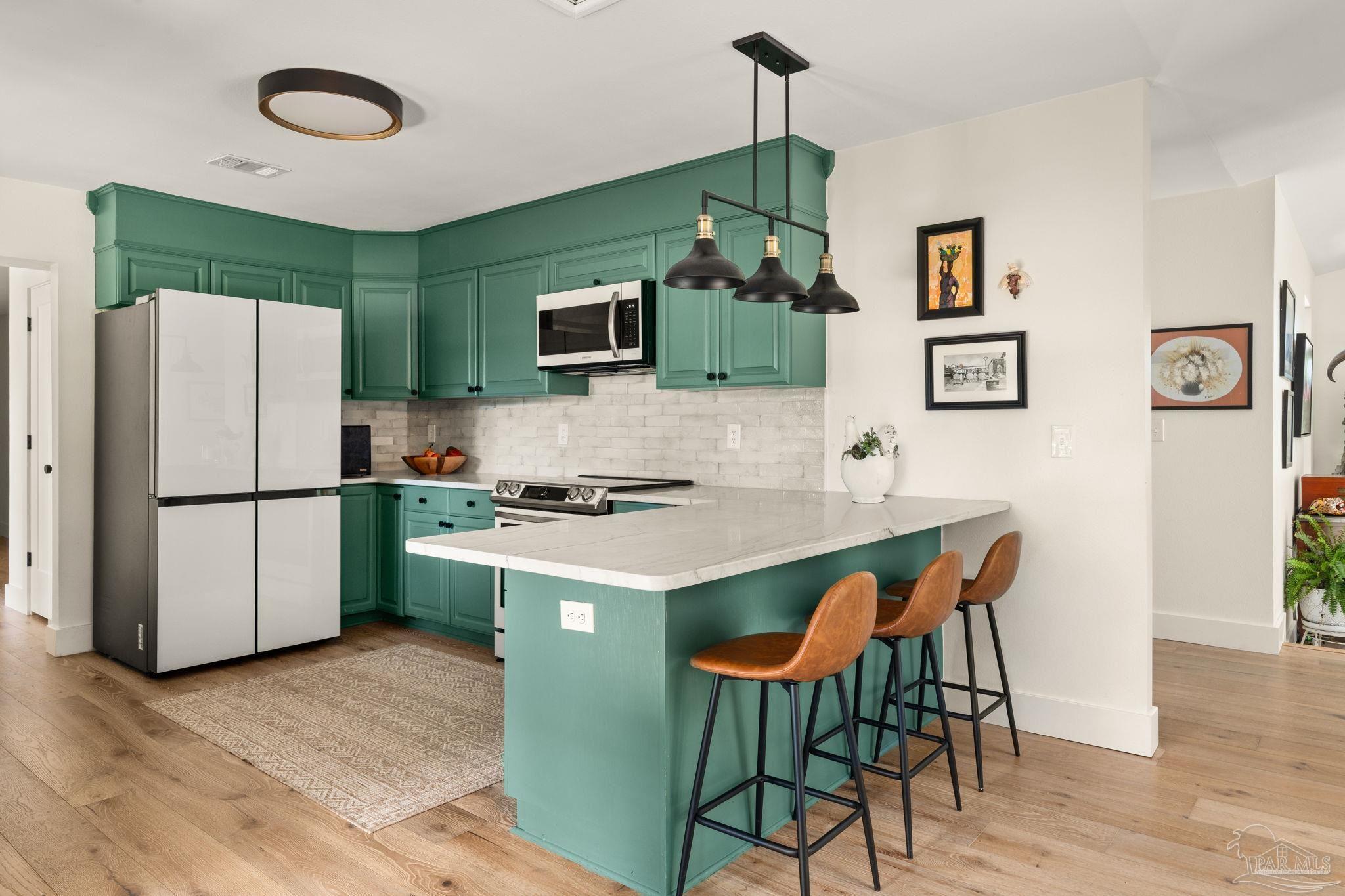 7716 Sunshine Hill Road Molino, FL 32577 - Photo 2 of 37 a kitchen with stainless steel appliances a stove a refrigerator a microwave a dining table and chairs with wooden floor