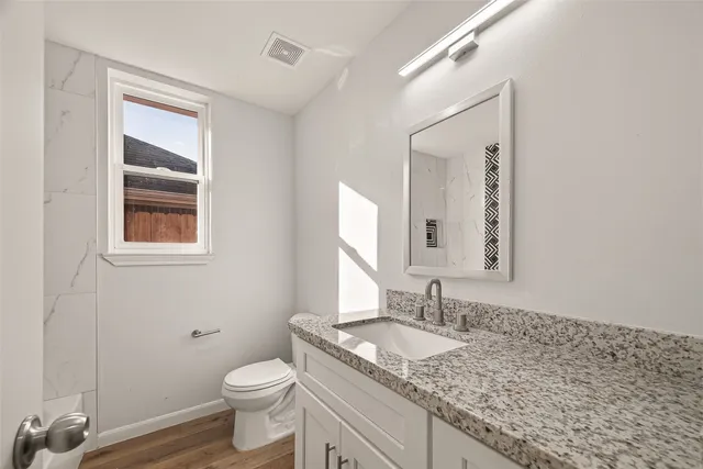 a bathroom with a granite countertop sink toilet and mirror