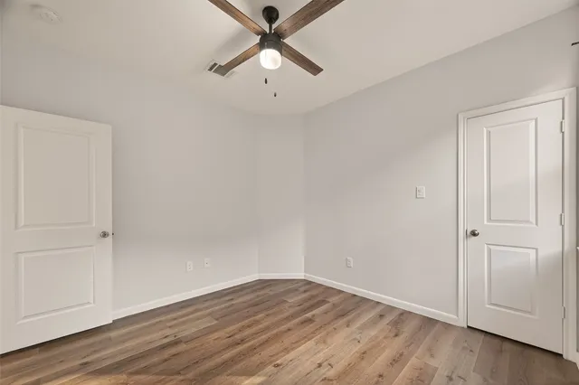 an empty room with wooden floor closet and windows