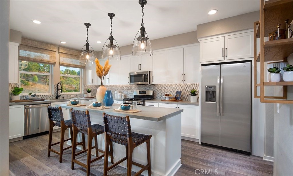a kitchen with stainless steel appliances granite countertop a sink a center island a refrigerator and a stove