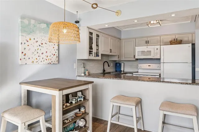 a kitchen with stainless steel appliances granite countertop a sink a stove a refrigerator cabinets and chairs