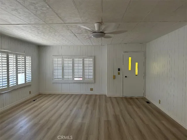a view of an empty room with a window and wooden floor
