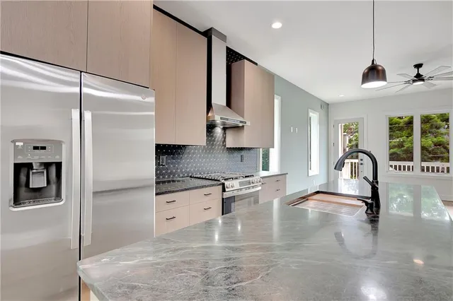 a kitchen with stainless steel appliances granite countertop a sink a stove and a refrigerator