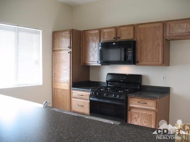 13827 Ocotillo Road Desert Hot Springs, CA 92240 - Photo 4 of 15 a kitchen with granite countertop a stove a microwave a sink and cabinets