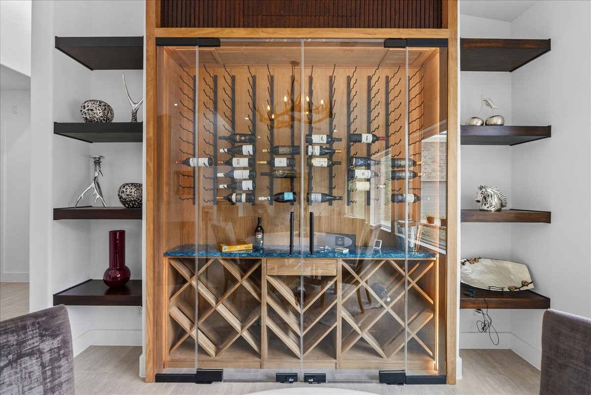 7627 Scott Avenue Manvel, TX 77578 - Photo 11 of 50 The elegant dining area features a custom climate controlled wine display with integrated lighting, wood accents, and floating shelving.