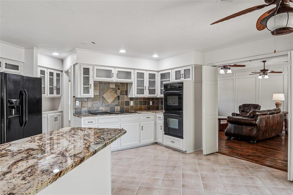 1006 Cochran Road Argyle, TX 76226 - Photo 6 of 40 Kitchen with loads of cabinets, granite countertops and Indian slate backsplash