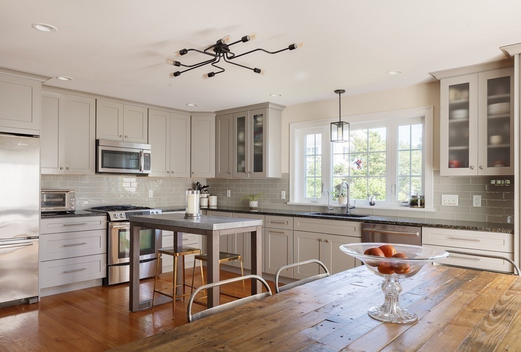 79 Bay State Road Arlington, MA 02474 - Photo 3 of 31 a kitchen with stainless steel appliances granite countertop a stove top oven a sink dishwasher a dining table and chairs with wooden floor