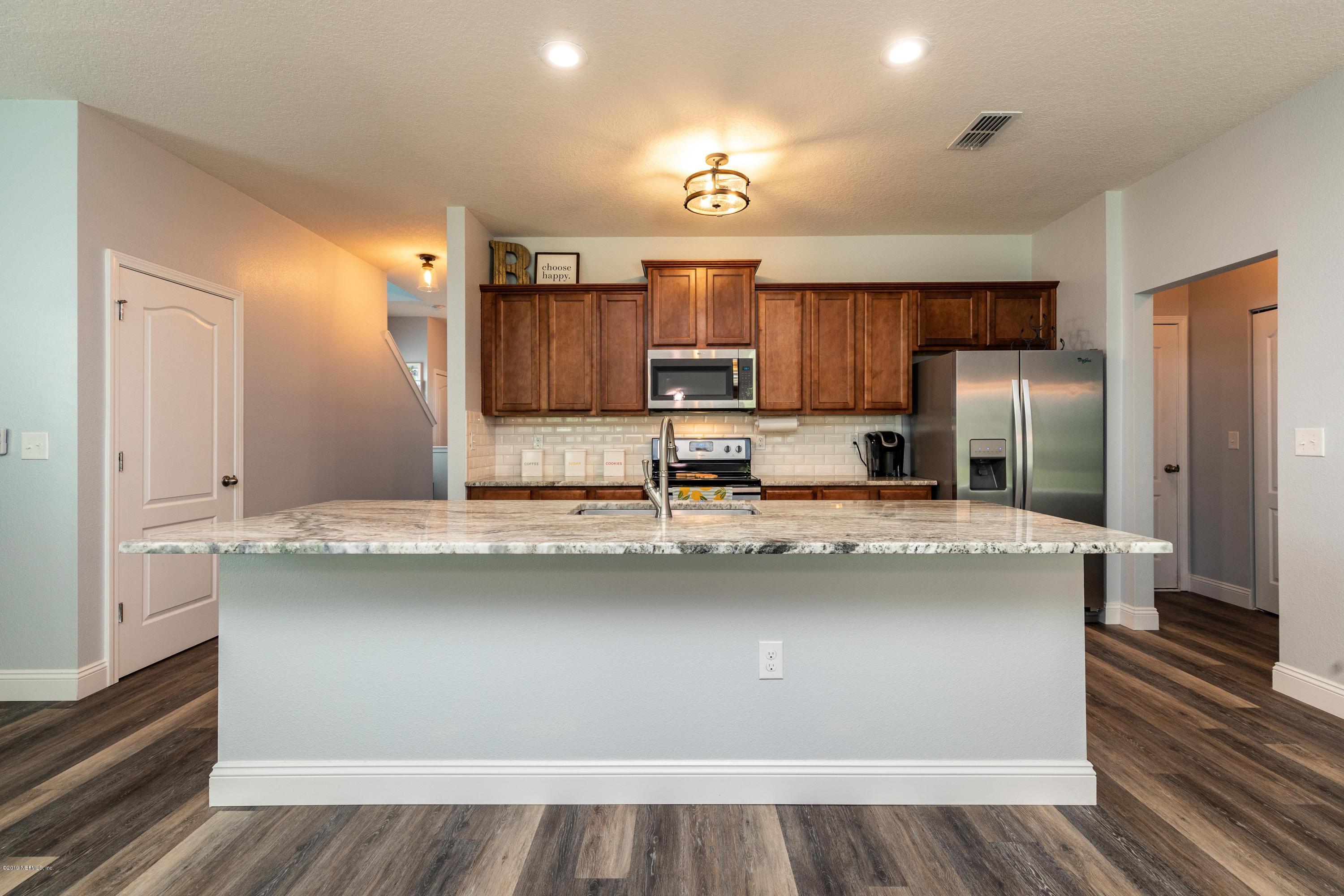 194 Ashby Landing Way St. Augustine, FL 32086 - Photo 11 of 41 a kitchen with kitchen island granite countertop a sink stove and refrigerator