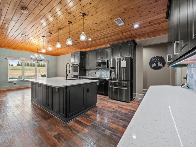 a kitchen with stainless steel appliances granite countertop a refrigerator a sink a stove and a wooden floors