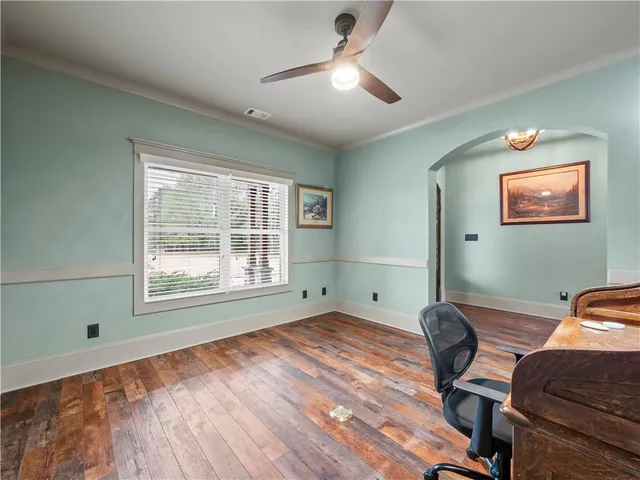 a workspace with furniture a ceiling fan and wooden floor