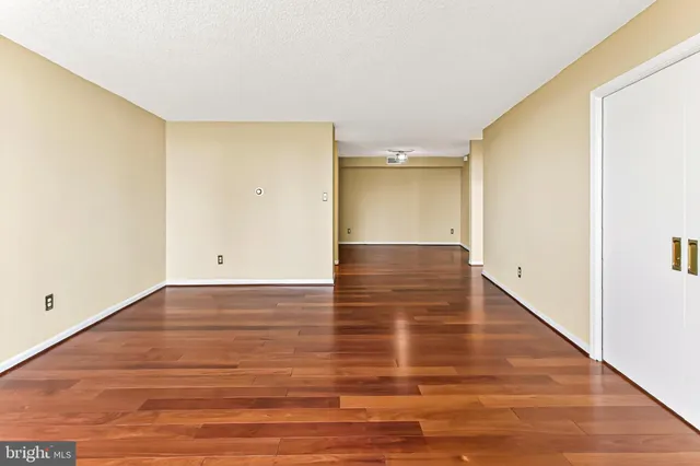a view of empty room with wooden floor and fan