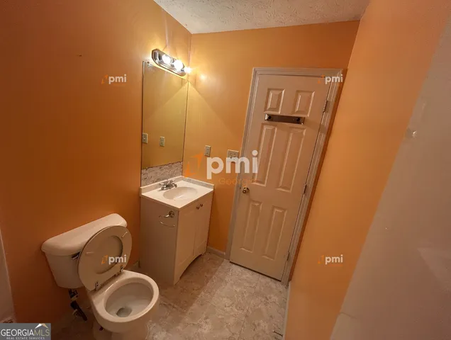 a bathroom with a toilet a sink a mirror and vanity