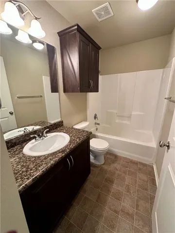 a bathroom with a granite countertop sink a toilet and a mirror