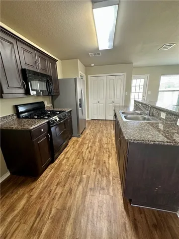 a kitchen with granite countertop wooden cabinets and a stove top oven