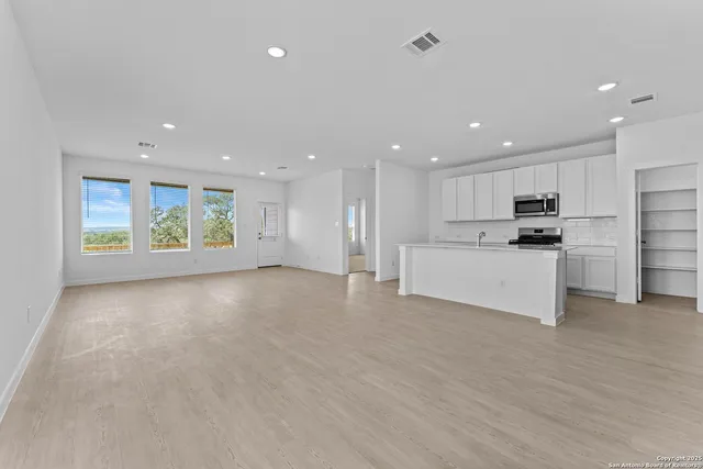 a view of kitchen with kitchen island wooden floor center island and stainless steel appliances
