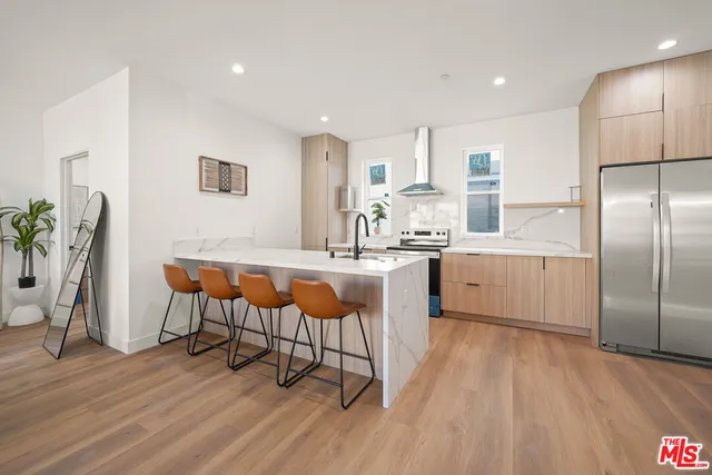 a kitchen with stainless steel appliances kitchen island granite countertop a table chairs sink and cabinets
