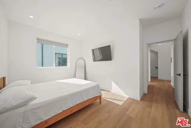 a bedroom with a bed and a flat tv screen on dresser