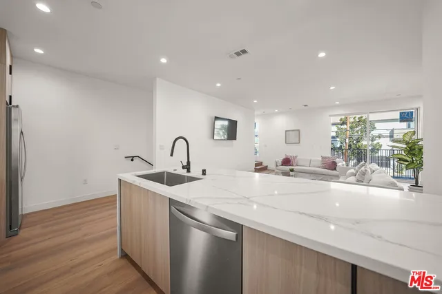 a kitchen with stainless steel appliances granite countertop a sink a stove a dining table and chairs