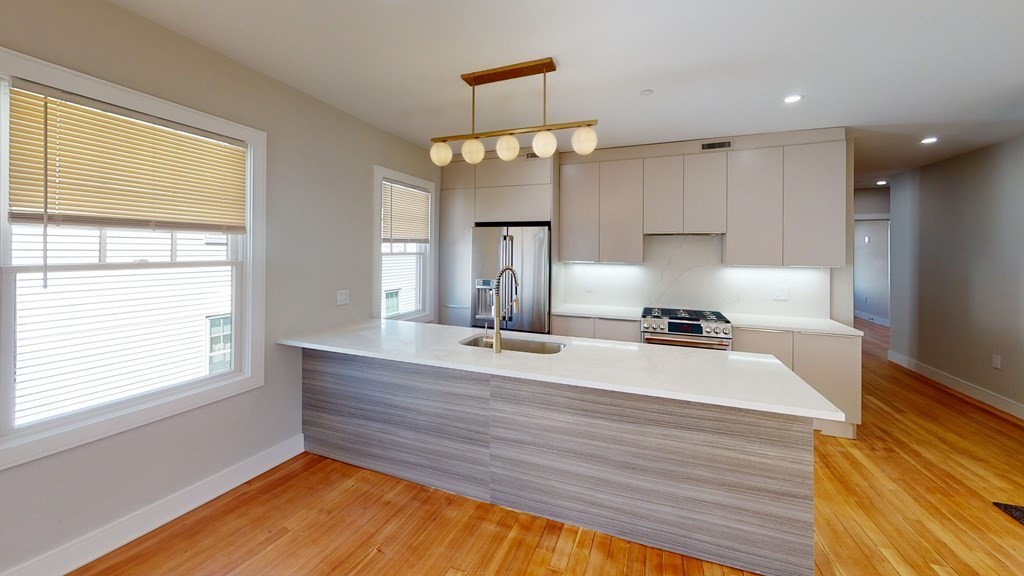 a room with kitchen island a large window appliances and cabinets