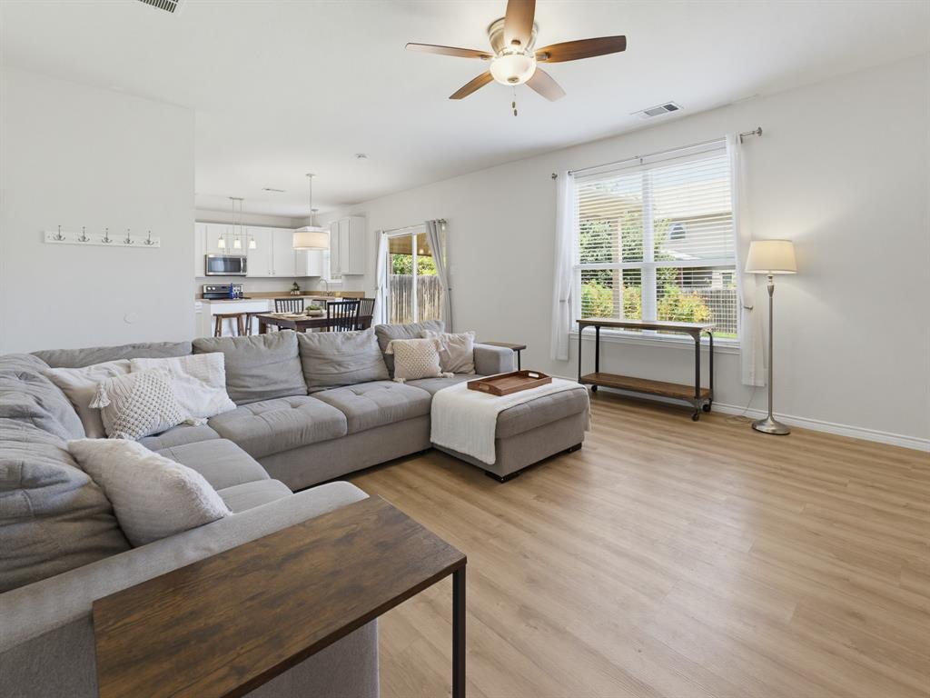 13268 Fencerow Road Fort Worth, TX 76244 - Photo 15 of 25 Open-concept living area featuring wood-finish flooring, a ceiling fan with integrated lighting, and a large window with white blinds